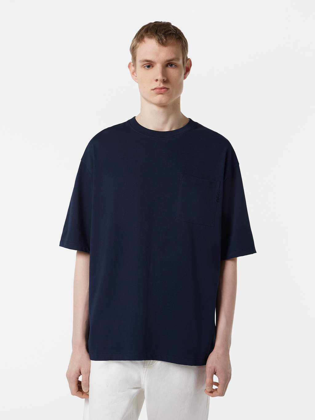 Person wearing a navy blue t-shirt and white pants on a light gray background