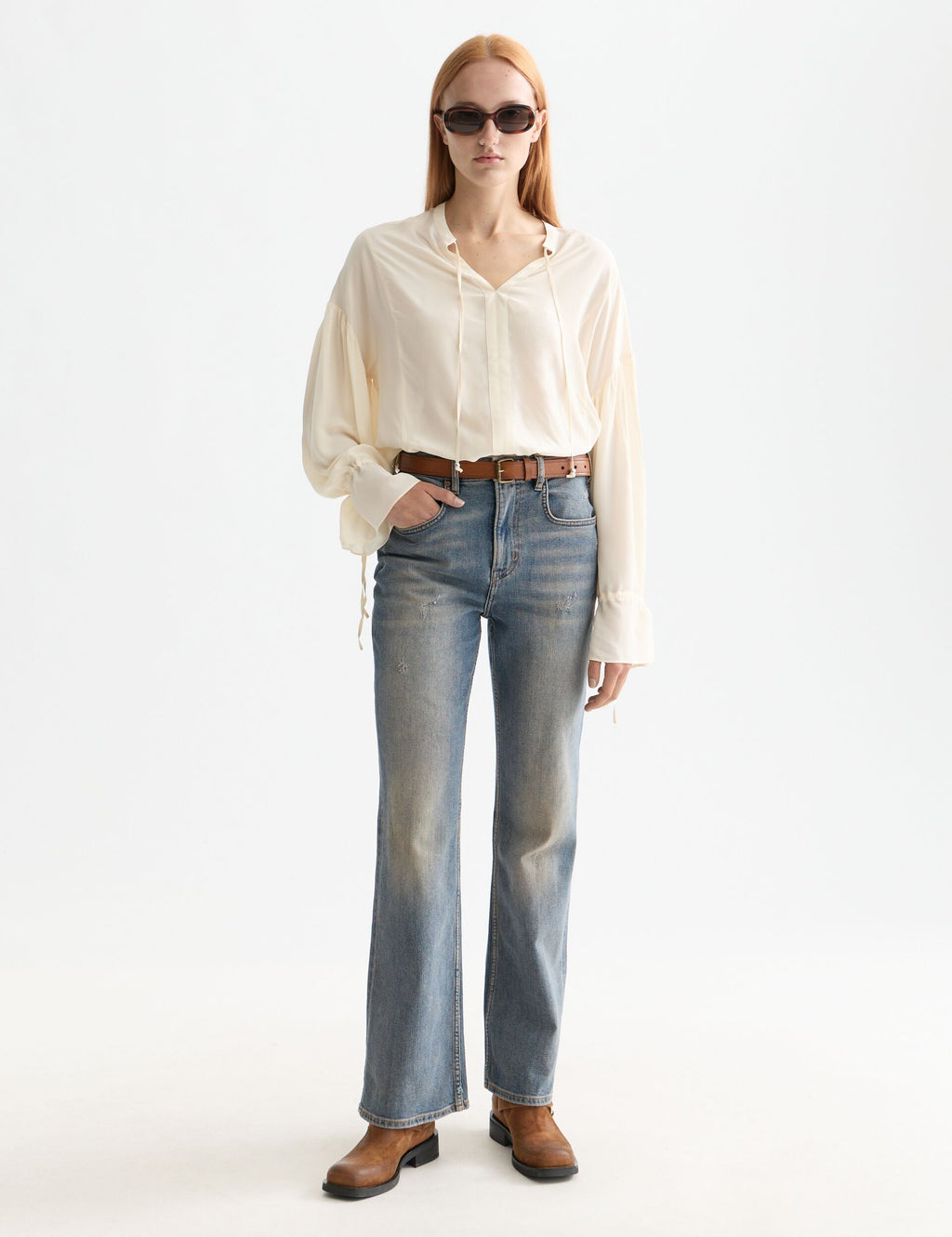 Person wearing a white shirt, blue jeans, and sunglasses on a white background