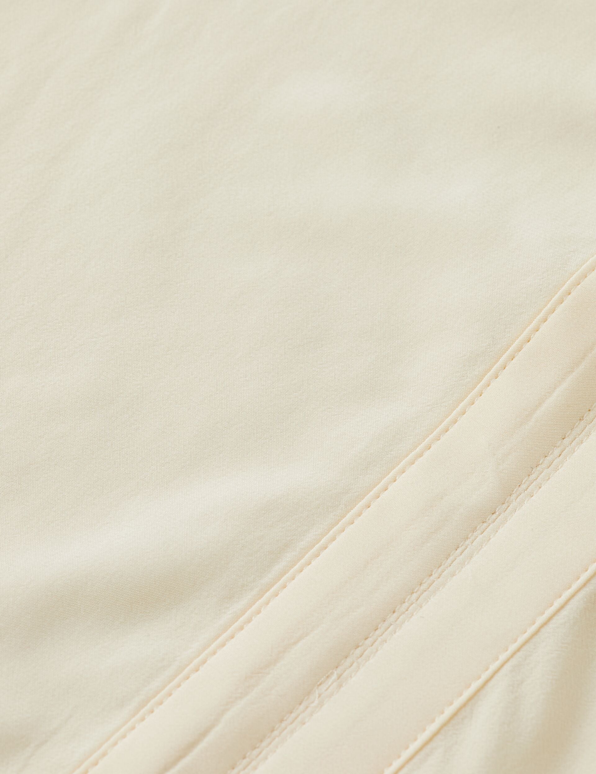 Close-up of beige fabric with a subtle texture and stitching detail.