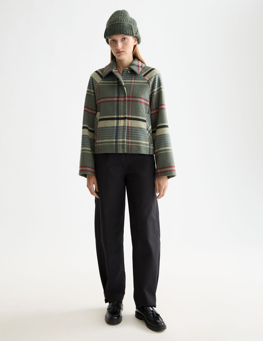 Person wearing a plaid shirt and black pants on a white background