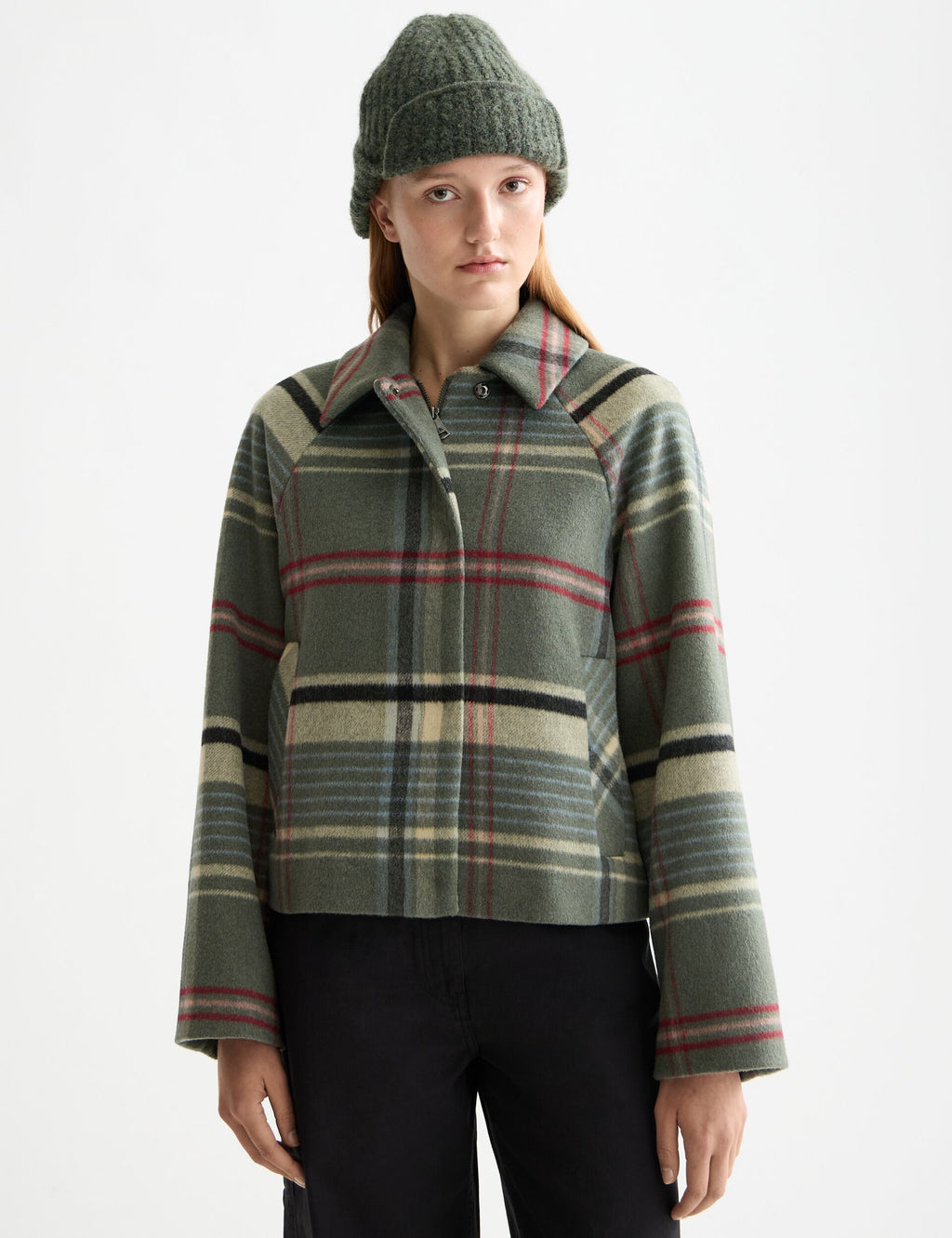 Person wearing a plaid jacket and beanie on a white background