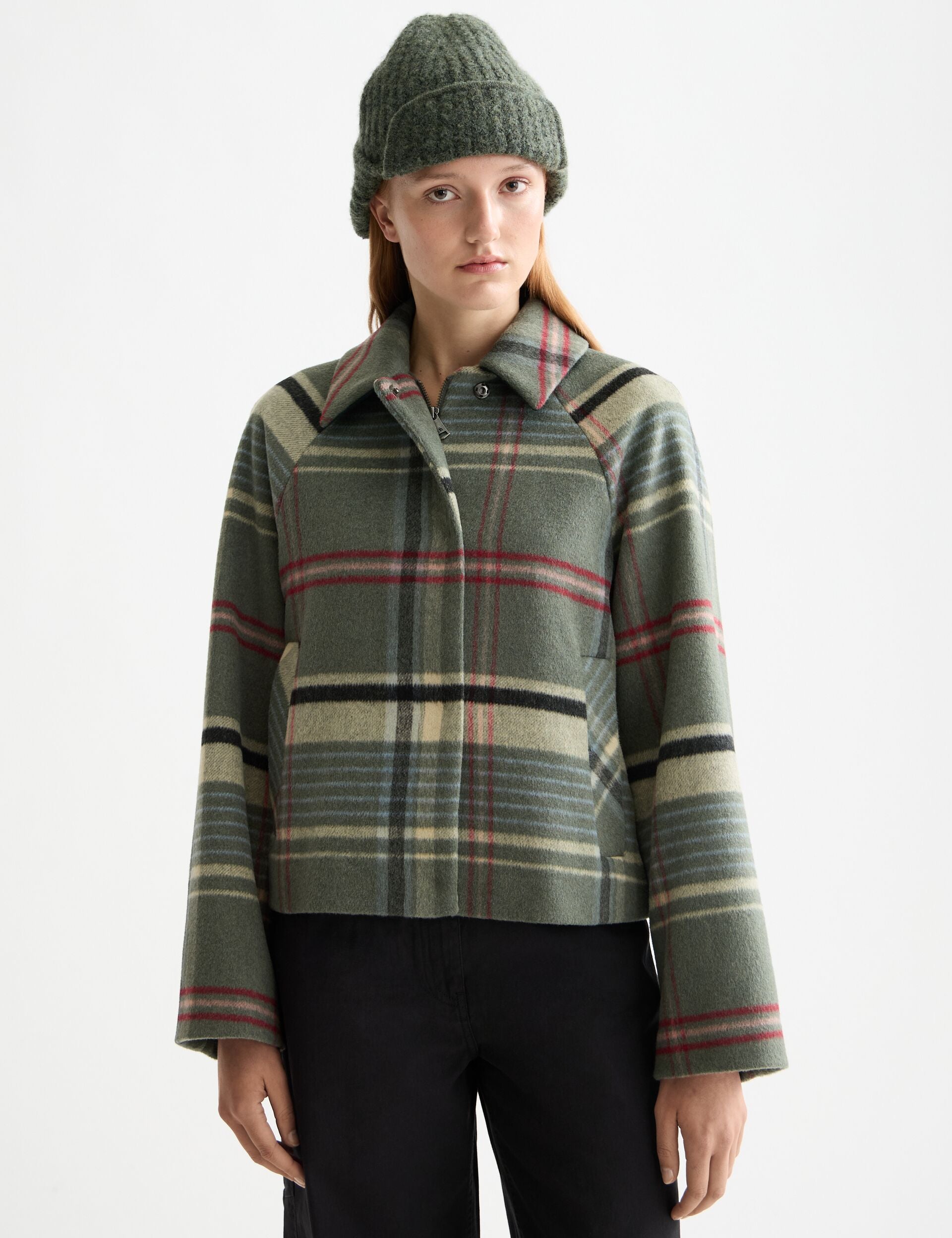 Person wearing a plaid jacket and beanie on a white background
