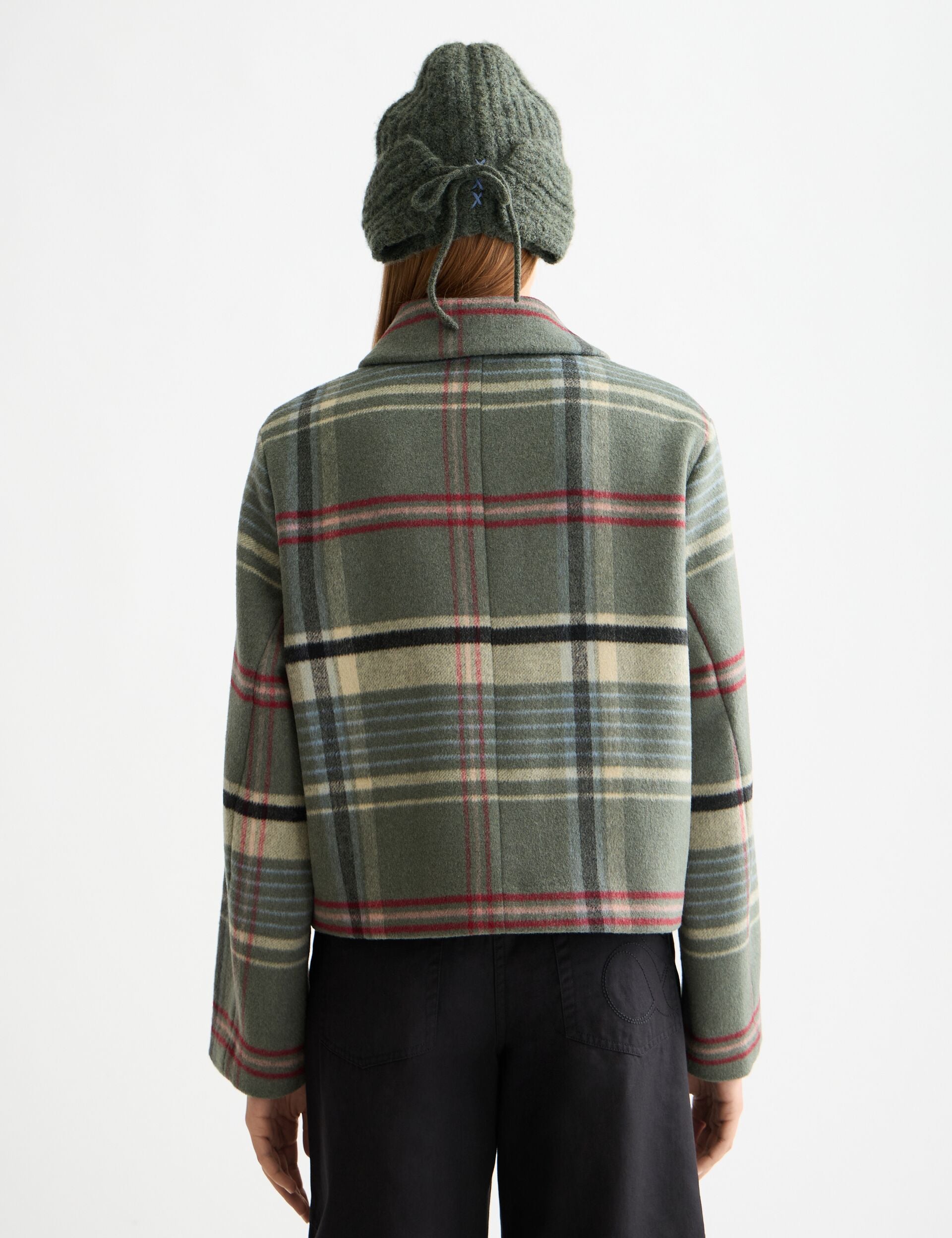 Person wearing a green plaid jacket on a white background