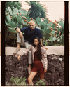 male model in blue button up shirt and female model in matching red set posing in front of cacti