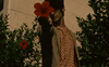 background image featuring male model in patterned shirt holding out a red flower