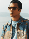 male model posing in front of waterfront wearing sunglasses